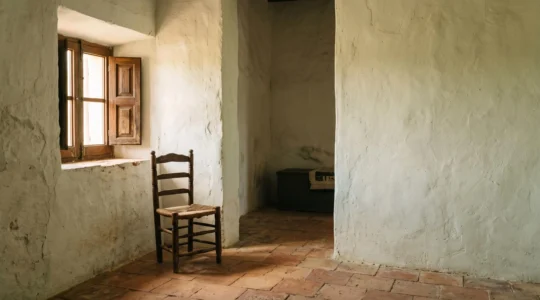 Interior de una casa antigua con paredes encaladas que reflejan suavemente la luz natural del sol